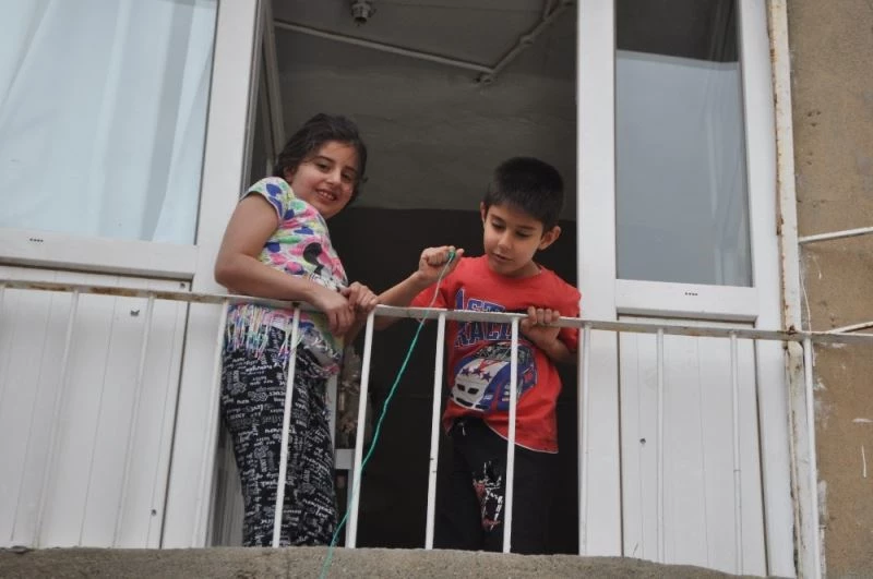 Sokağa çıkamayan çocuklar şekerlerini sepet sarkıtarak aldı
