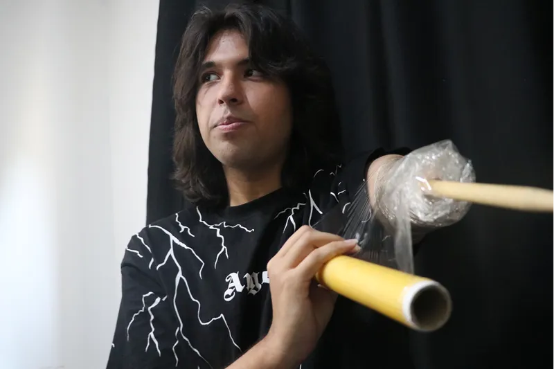 Depremde kolunun büyük bölümünü kaybeden genç, streç filmle sabitlediği bagetle bateri çalıyor